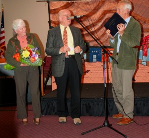 Fran Cheslock, left, receives flowers and a handmade leatherbound photo album Chester Rotary President Ron Thiessen, center, and past President Malcolm Summers. Summers, a bookbinding craftsman, created the album. Photo by Cynthia Prairie