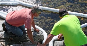 From left, Joel Brookes and an environmental cleanup worker lay booms Wednesday morning.