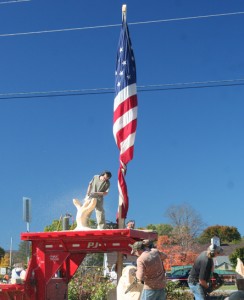 One carver stands on platform below a gigantic American flag.