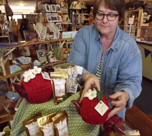 Artist of the Month Joan Lester sets up her display of tea-cozies and tea blends at the River Artisans Cooperative shop.