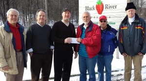 From left, Kevin Kuntz, vice president of Black River Good Neighbor Services; Mark Curran and Stephen Birge, owners of Black River Produce; Peter LaBelle, president of BRGNS; Robert Evens, BRGNS treasurer; and Charles Hastings, director of BRGNS. Birge passes the deed to donated land to LaBelle.