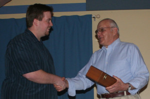 Yosemite Engine Company President Ben Whalen presents Harry Goodell with a bottle of 1969 Glenlivet Scotch.
