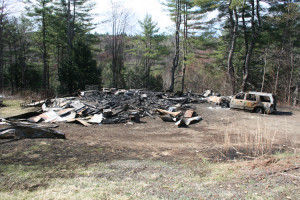 A gutted car with its tires burned off sits in front of the burned out garage in what officials characterize as a drug related fire.