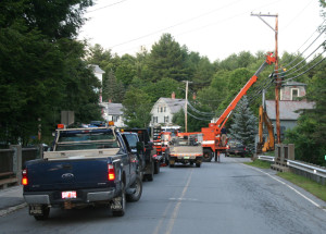 A Green Mountain Power crew secures a grip on the pole to keep it in place while a town crew digs for the broken water main.