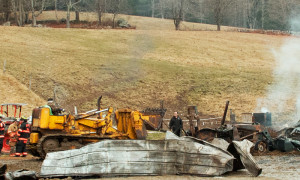 On his yellow bulldozer, Dick Alexander backs away from the building, pulling a burned tractor