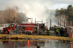 Chester Engine 1 draws water from a farm pond as firefighters pour water on hot spots in the background