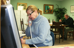 Emily Huff takes a phone call while Select Board member Skip Lisle peruses documents. Photos by Cynthia Prairie
