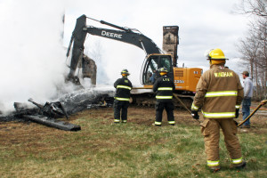 Firefighters mop up with the help of an excavator