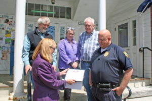 Marji Graf, lower left, reads the Safewise certificate as (clockwise) select board members John DeBenedetti and Heather Chase, Town Manager David Pisha and Police Chief Richard Cloud lookon