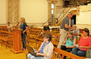 Carol Lind, at the podium, begins her talk about Iberdrola's wind project while Grafton Select Board member Skip Lisle hands out a map showing distances from wind towers
