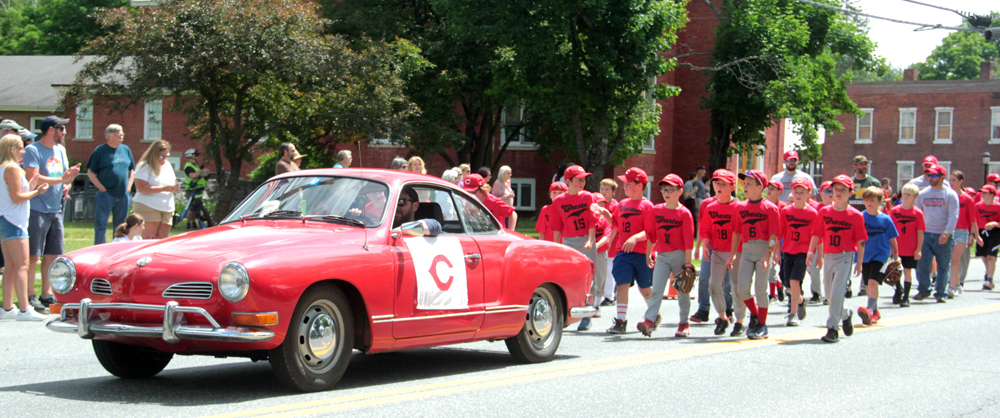 The Chester Cardinals Little League team is escorted on the parade route by a bright red Karmann Ghia.